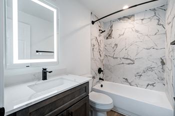 A white sink is in a marble bathroom.
